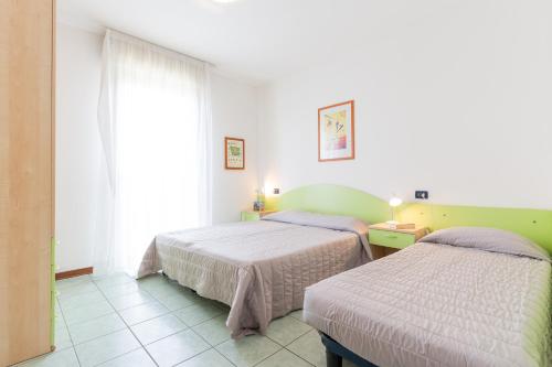 una camera da letto con due letti e una finestra di TIGLI Lido Altanea a Caorle