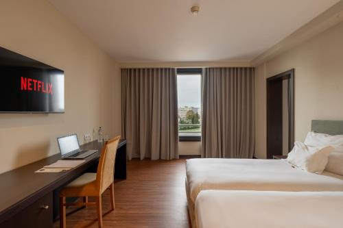 a hotel room with a bed and a desk with a laptop at Hotel Premium Porto Maia in Maia