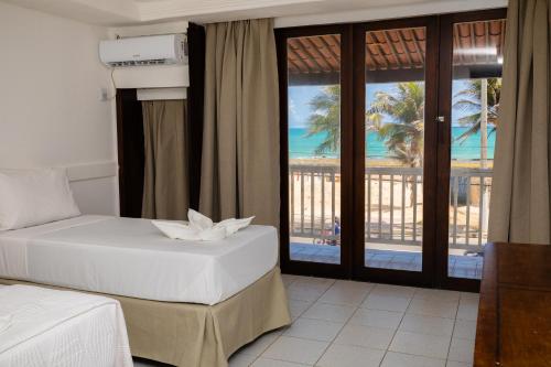 a bedroom with two beds and a view of the ocean at Sirius Beach Hotel in Natal