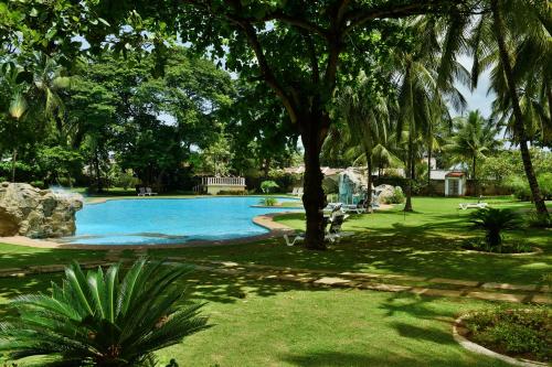 a swimming pool in a park with a tree at Pestana Miramar São Tomé in São Tomé