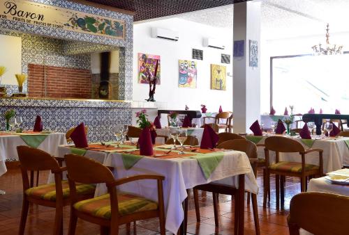 a dining room with tables and chairs with red napkins at Pestana Miramar São Tomé in São Tomé