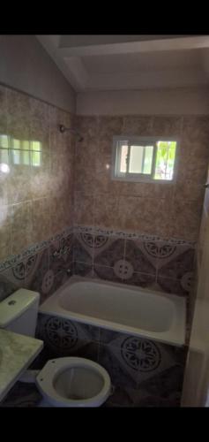 a bathroom with a tub and a toilet and a window at Delsur in Neuquén