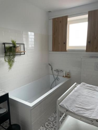 a white bathroom with a tub and a window at L 'Évasion in Saint-Cyprien