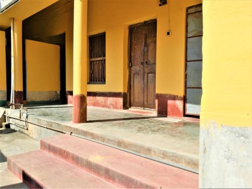 a building with yellow walls and a wooden door at The OLD house in Bolpur
