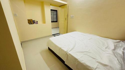 une chambre avec un lit blanc et un miroir dans l'établissement Maruthi Comforts, à Bangalore