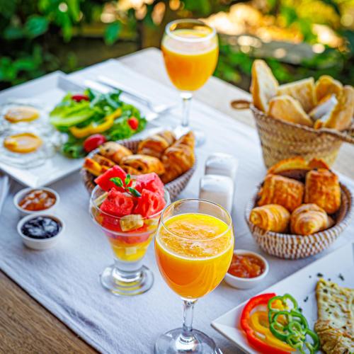 una mesa con dos vasos de zumo de naranja y comida en Keur Saloum Resort, en Toubakouta