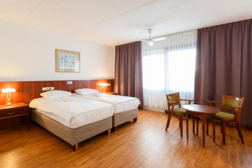 De Rijper Eilanden في دي رايب: غرفة فندق بها سرير وطاولة وكراسي