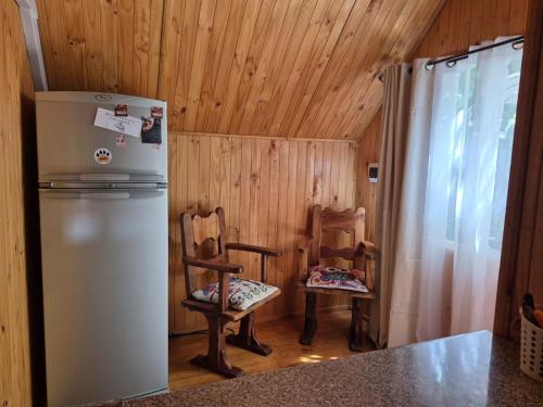 a kitchen with two chairs and a refrigerator at Carolin Cacao - Cabaña Nogal in San José de Maipo