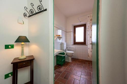 a bathroom with a toilet and a lamp on a table at Il Borgo Del Lupo Relax Family Apartments in Tuscany with Restaurant & Swimming Pool in Sarteano