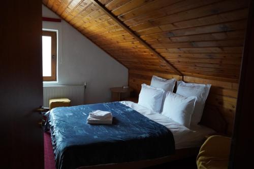 a bed in a room with a wooden ceiling at Pensiunea Kalinder in Buşteni