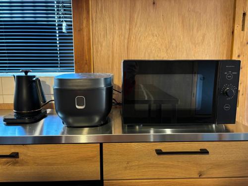 ŌwadaにあるHostel Inn かすみがうら 仁左ェ門のカウンターの上に電子レンジがあり、その隣に鍋がある