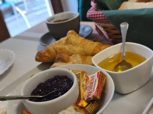 Un plato de comida con dos tazones de mermelada y pan. en Pensiunea Kalinder, en Buşteni