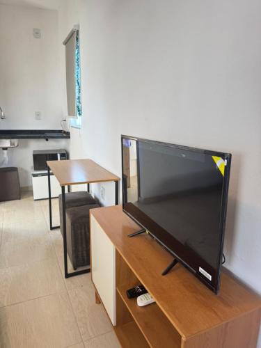a flat screen tv sitting on top of a wooden entertainment center at Park e Mar Studio quarto 1 in Penha