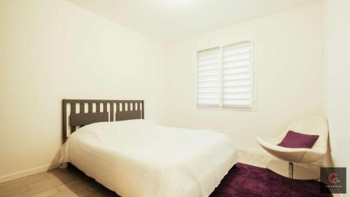 a white bedroom with a bed and a chair at Sanguinet - Élégante maison pour 6 personnes PMR in Sanguinet