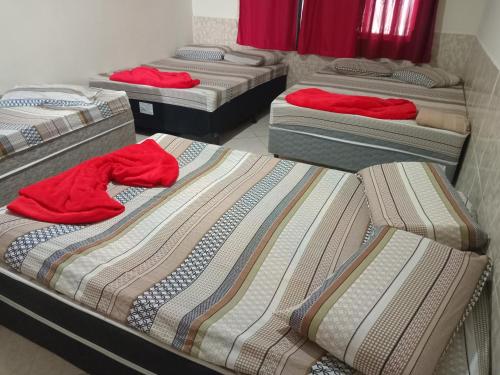 a group of four beds in a room at Casa Neia Castro com Piscina e garagem perto da Basilica in Aparecida