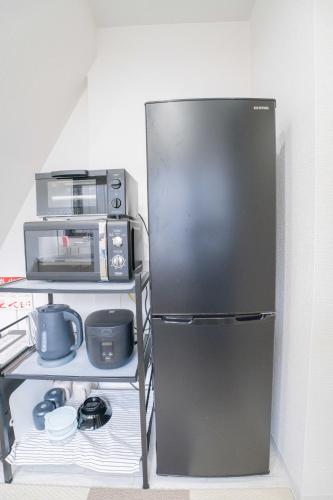 a black refrigerator in a kitchen with a microwave at Nagasaki Central House in Nagasaki