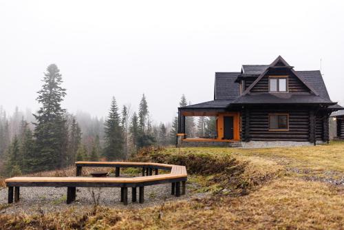 ein Blockhaus mit zwei Bänken davor in der Unterkunft Blackwood Retreat in Neagra Şarului
