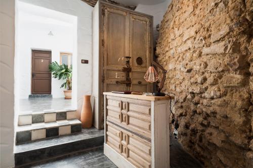 a kitchen with a wooden cabinet and a stone wall at La Fonda Antigua ADULTS ONLY in Vejer de la Frontera