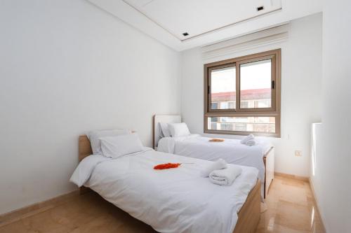 Duas camas num quarto com paredes brancas e uma janela em Relax & Sea View à 2 Pas de la Marina em Tânger