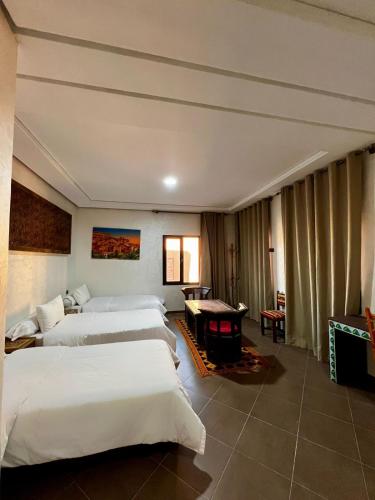 a hotel room with two beds and a desk at Hôtel LAKASBAH Ait Ben Haddou in Aït Benhaddou
