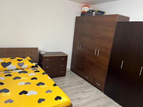 una camera da letto con un letto con una coperta gialla e armadi marroni di Alex Apartment a Balş