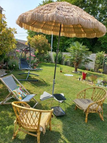 two chairs and an umbrella in the grass at Les Hirondelles in Saint-Georges-sur-Layon