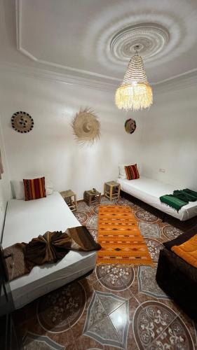 a living room with two beds and a chandelier at Black Pearl surf yoga and skate house in Tamraght Ouzdar