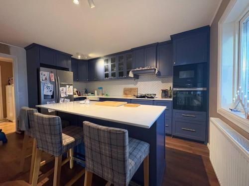 Kungsbacka Företagsbostad في كونغْسباكا: مطبخ مع دواليب زرقاء وجزيرة مطبخ مع كراسي