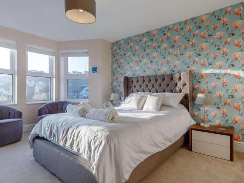 a bedroom with a large bed with a floral wallpaper at Sea View House in Cornwall Fishing Village in St Austell