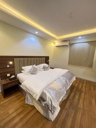 a bedroom with a large white bed with a wooden floor at شقق العرين للشقق المخدومة in Jeddah