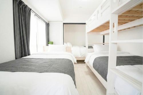 two beds in a bedroom with white walls at Nagasaki Central House in Nagasaki