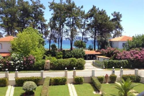 a fence in front of a garden with trees at Nerida House Salonikiou Beach in Akti Salonikiou