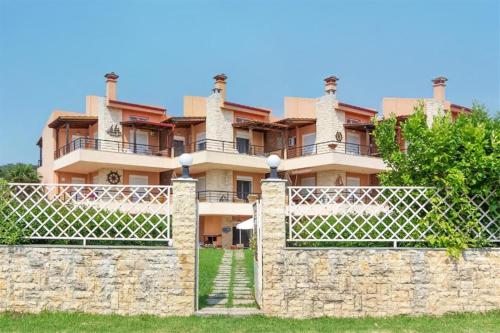 a large building behind a stone wall with a gate at Nerida House Salonikiou Beach in Akti Salonikiou