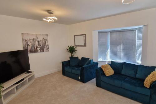 a living room with two blue couches and a flat screen tv at Peterborough - House - Sleeps 8 - Parking - Garden in Peterborough
