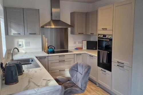 a kitchen with white cabinets and a marble counter top at Peterborough - House - Sleeps 8 - Parking - Garden in Peterborough