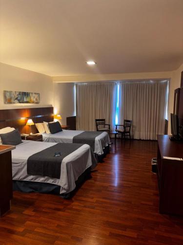 a hotel room with two beds and a television at Puerto Amarras Hotel & Suites in Santa Fe