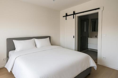 a bedroom with a white bed and a bathroom at Hof van Sassenbroek in Borgloon