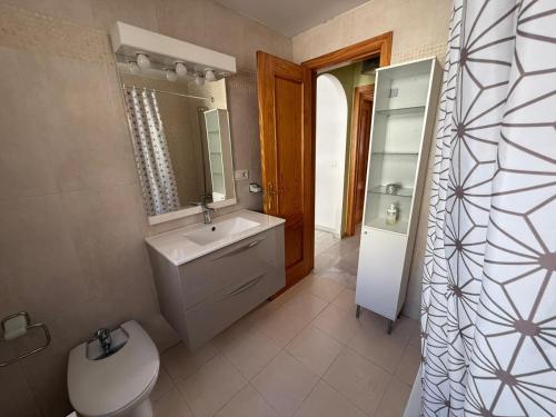 een badkamer met een wastafel, een toilet en een spiegel bij Casa Familiar Atarfe in Atarfe