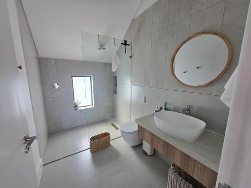 a white bathroom with a sink and a mirror at Yzer Heights Relaxed Luxury Stay in Yzerfontein