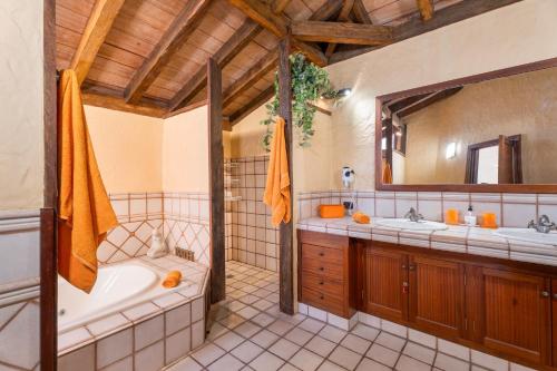 a bathroom with a tub and two sinks and a mirror at Finca Toledo in Las Zocas