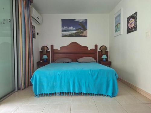 une chambre avec un lit avec une couverture bleue dans l'établissement Ty Alice, à Sainte-Anne