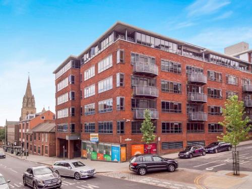 a large brick building with cars parked in a parking lot at Modern 2 BDR Flat in Nottingham City Centre with free parking in Nottingham