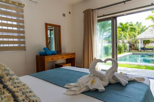 two towel swans are sitting on a bed at Summer Palms Villa in Flic-en-Flac
