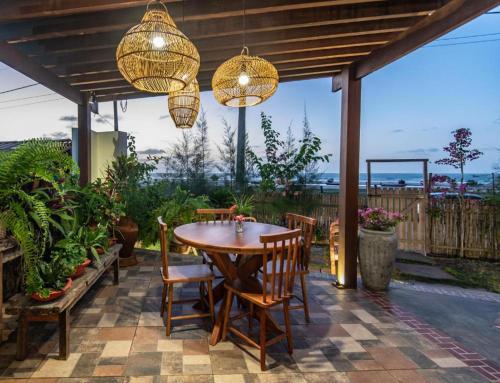 a patio with a wooden table and chairs and chandeliers at Casa Maria Areia Boutique in Camocim