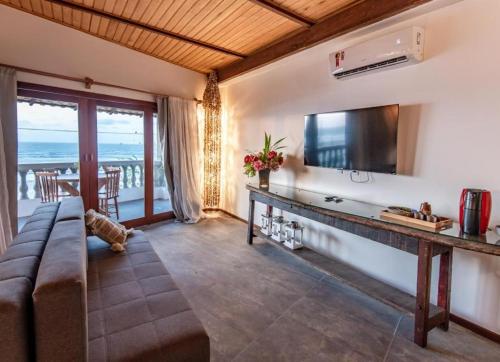 a living room with a couch and a television at Casa Maria Areia Boutique in Camocim