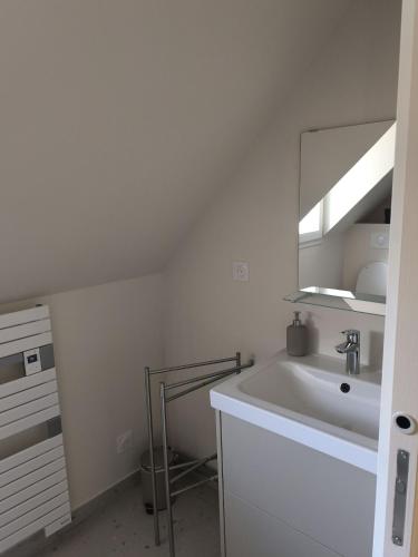 un bagno bianco con lavandino e specchio di Appartement résidence historique centre de Vernon a Vernon