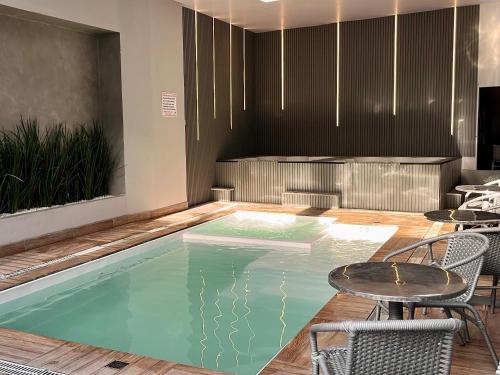 a pool in a room with chairs and a table at Pousada Duas Ilhas in Penha