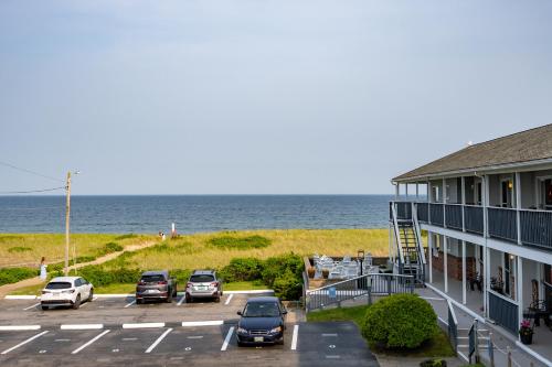 a parking lot with cars parked next to the ocean at Kebek 3 Oceanside Motel in Old Orchard Beach