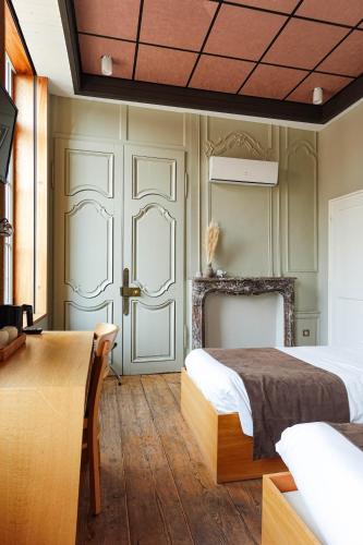 a bedroom with a bed and a table and a door at Hôtel - Restaurant Au Tonnelier in Bergues