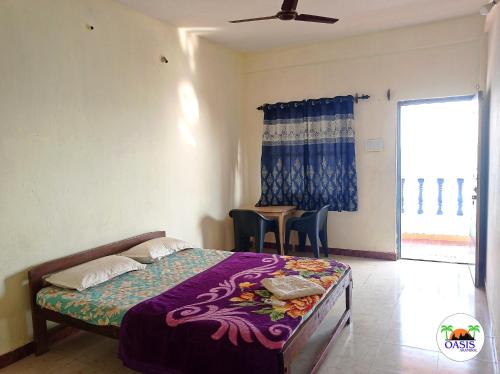 a bedroom with a bed and a table and a window at Oasis Arambol in Arambol